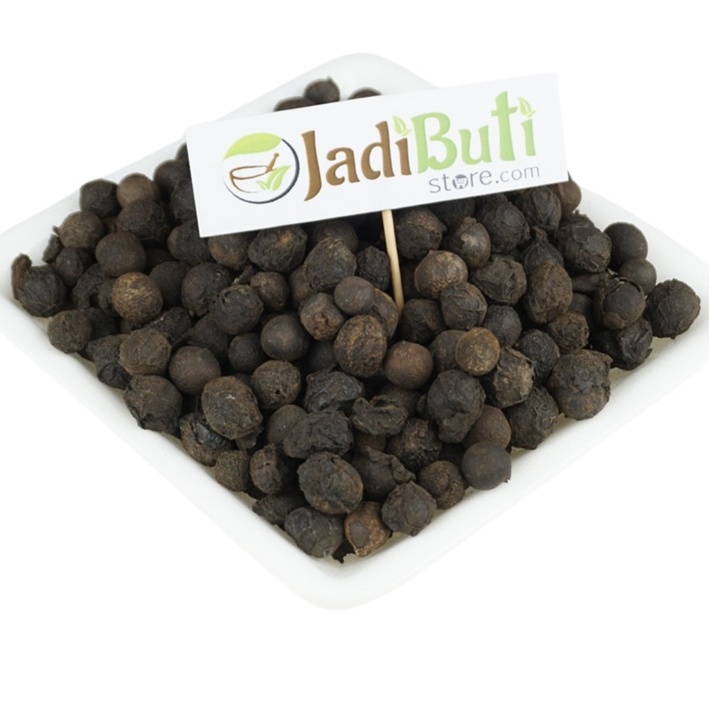 Sugandh Kokila dark rounded dried pieces on a white rectangular plate; species unverified — Jadibuti Store